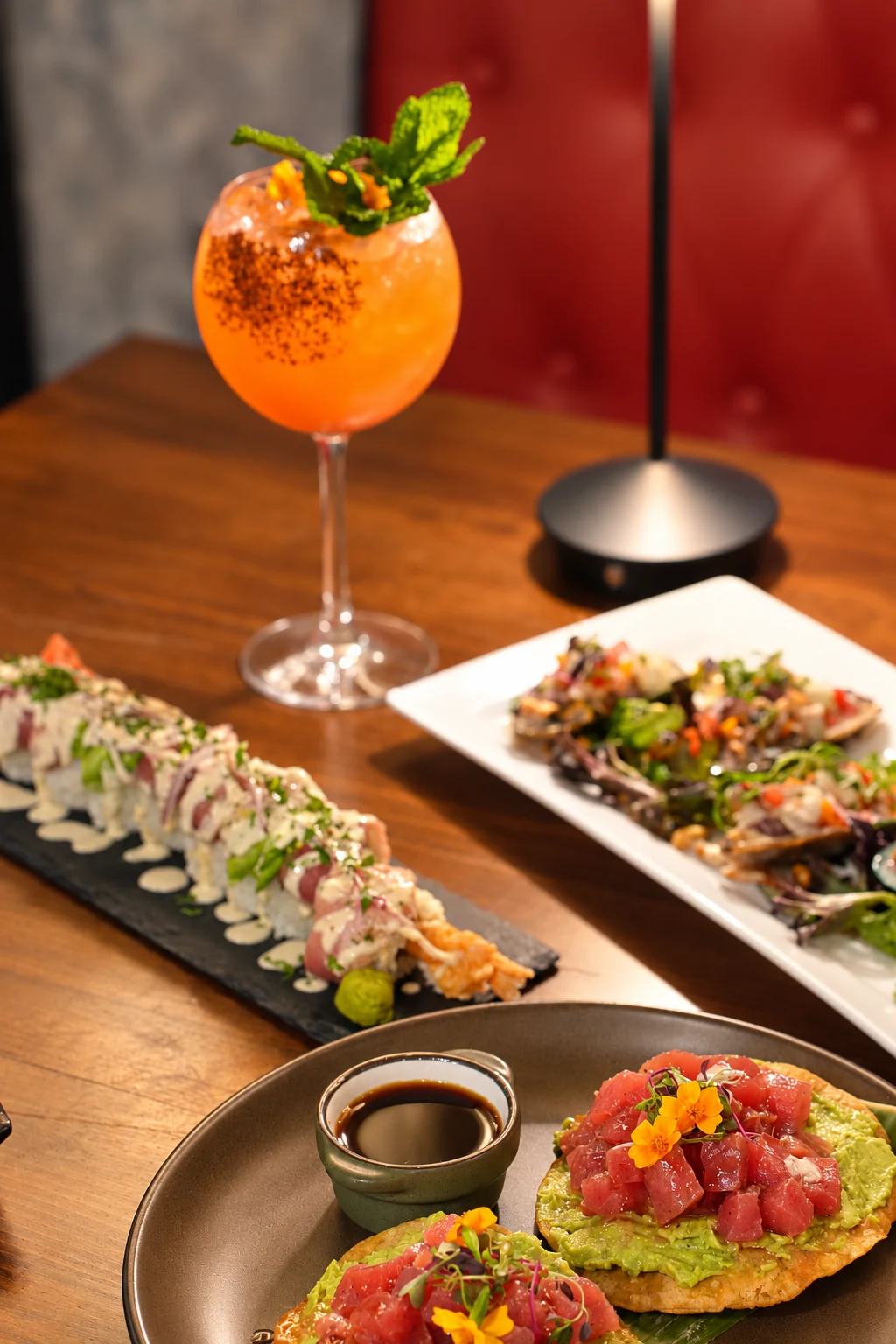 A spread of ALMA dishes and an orange cocktail